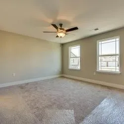 an empty room with windows and ceiling fan