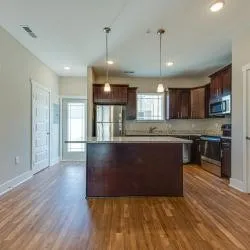 a kitchen with kitchen island granite countertop wooden floors stainless steel appliances a sink and a window