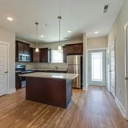 a large kitchen with stainless steel appliances granite countertop a refrigerator a stove a sink and a wooden floors