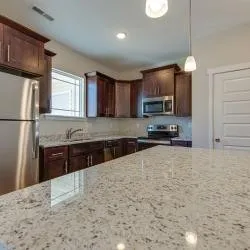 a kitchen with stainless steel appliances granite countertop a refrigerator a stove a sink dishwasher a oven with wooden cabinets and floor