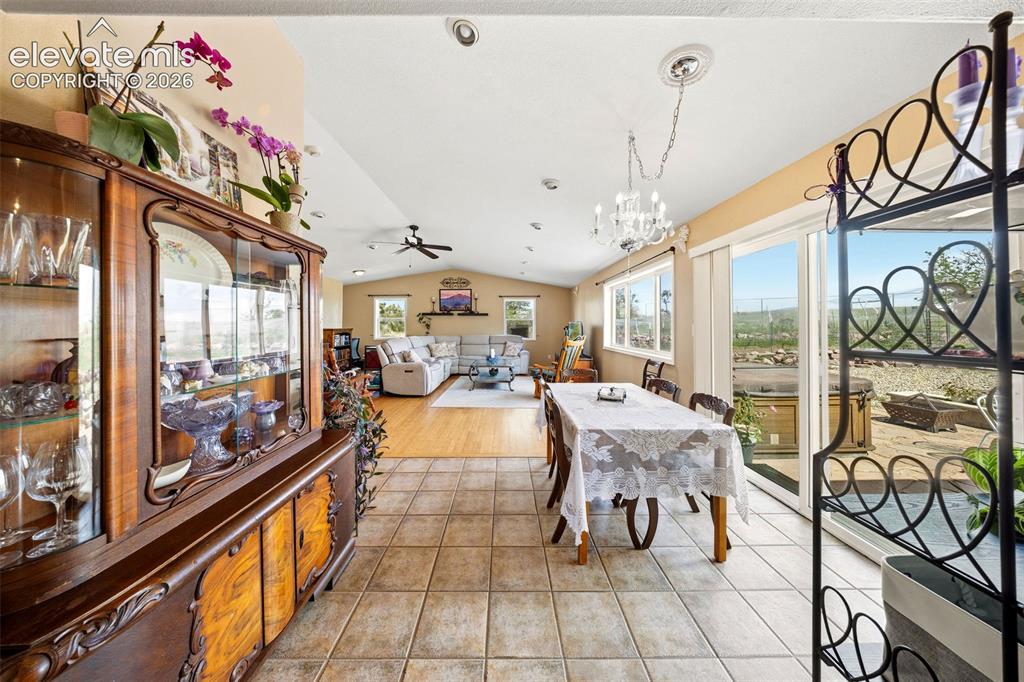 13075 Blaney Road South Peyton, CO 80831 - Photo 10 of 40 Spacious open-concept living area featuring a formal dining space with a chandelier, a living room with wood-finish flooring, and expansive windows offering outdoor scenery
