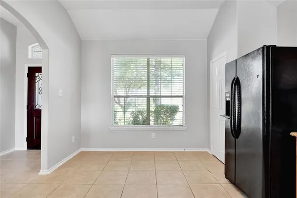 a view of an empty room with window and refrigerator