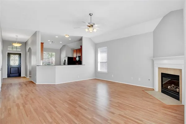 a view of a kitchen and an empty room with wooden floor