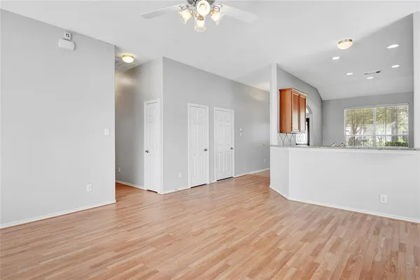 a view of an empty room with wooden floor and a window