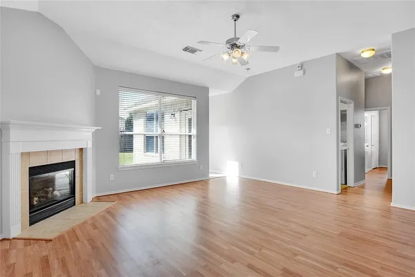 a view of an empty room with wooden floor and a fireplace