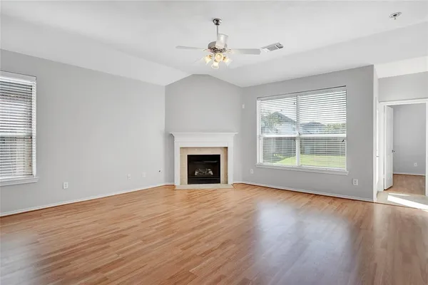 a view of an empty room with wooden floor fireplace and a window