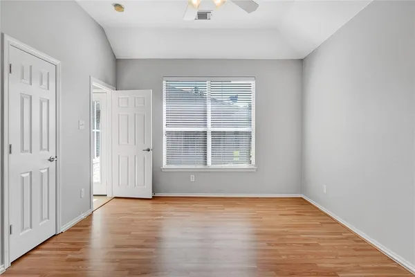 a view of empty room with wooden floor and fan