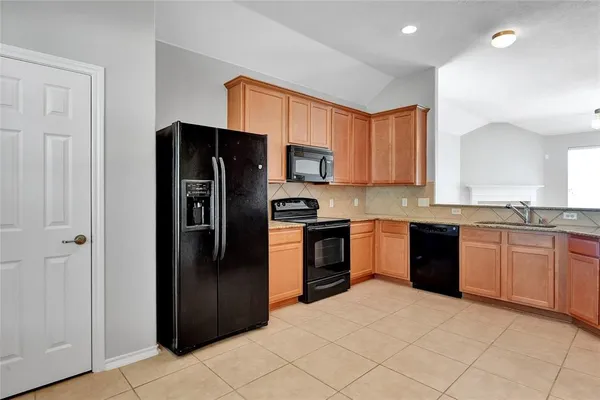 a kitchen with stainless steel appliances granite countertop a refrigerator stove top oven and sink