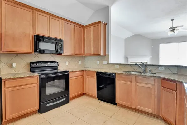 a kitchen with granite countertop a sink stove and microwave