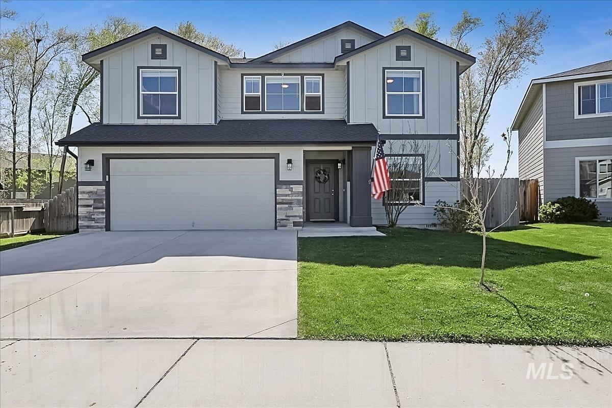 3401 Northwest 12th Avenue Meridian, ID 83646 - Photo 1 of 1 Contemporary two-story residence featuring light gray siding with dark trim accents, a two-car garage, stone veneer detailing, a concrete driveway, and a manicured front lawn
