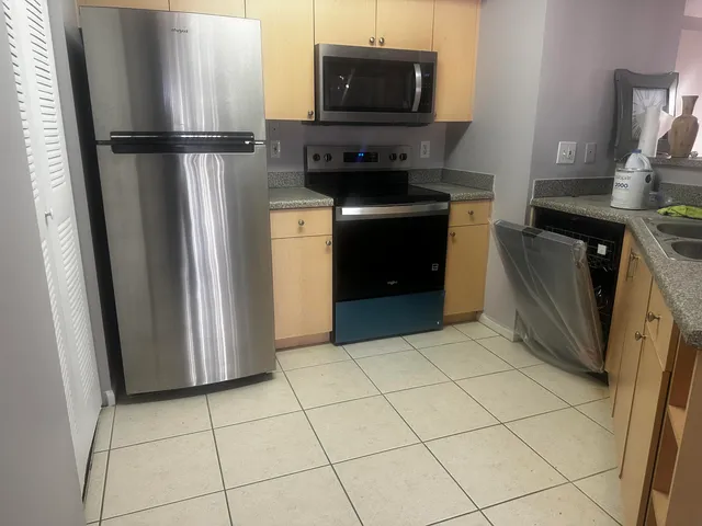 a kitchen with stainless steel appliances granite countertop a refrigerator and a stove top oven
