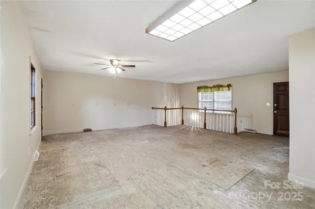 an empty room with windows and fan