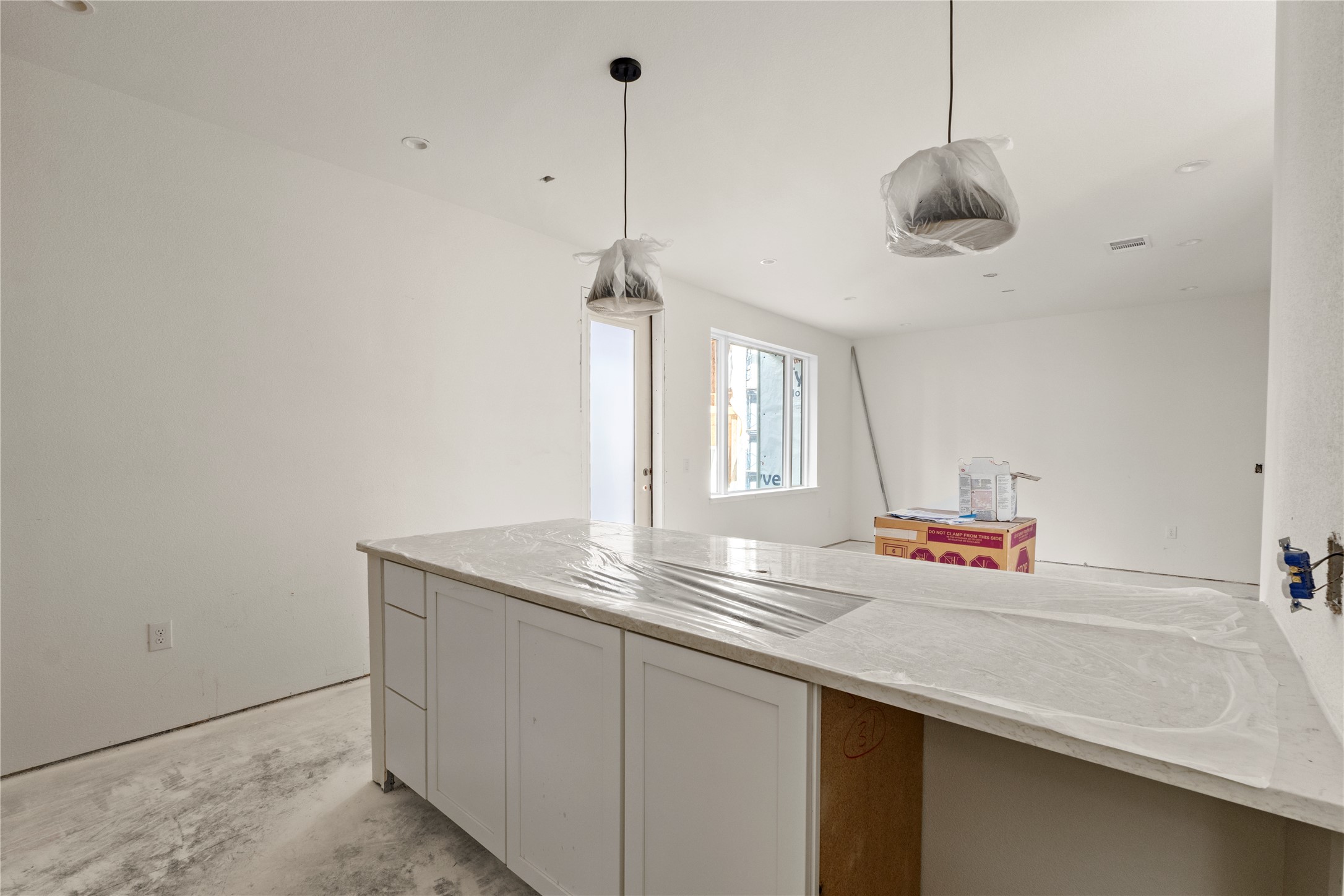 1180 Lott Avenue Austin, TX 78721 - Photo 6 of 40 Kitchen featuring unfinished concrete floors, light stone countertops, decorative light fixtures, and white cabinetry