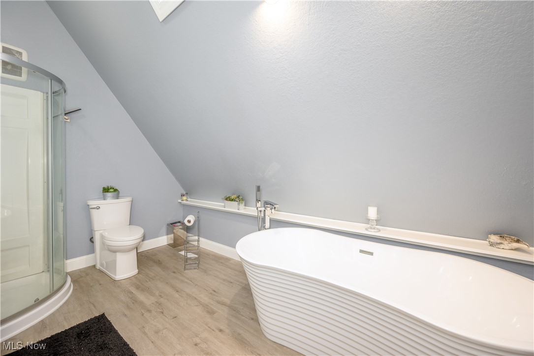 8731 Whipporwill Road Ravenna, OH 44266 - Photo 38 of 45 Bathroom with wood-type flooring, toilet, plus walk in shower, and vaulted ceiling