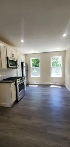 a kitchen with stainless steel appliances wooden floors and white cabinets
