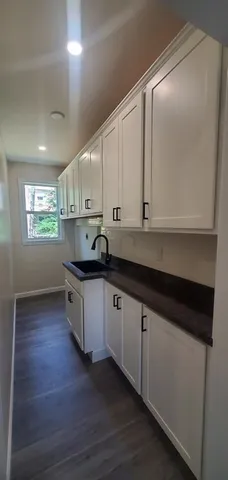 a kitchen with granite countertop white cabinets and a sink