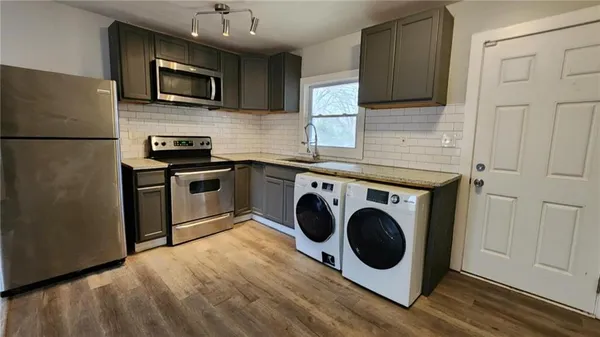 a kitchen with a refrigerator stove and wooden floor