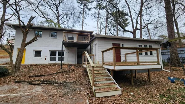 a view of an empty room with wooden floor and a kitchen