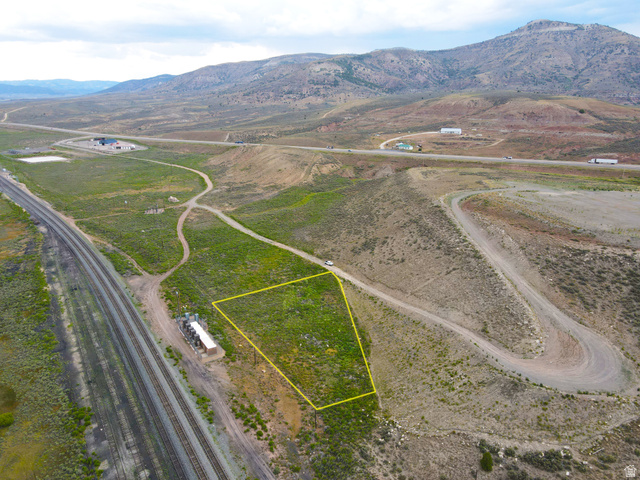 25315 South UDOT Access Road East Helper, UT 84526 - Photo 7 of 20 Expansive parcel of land bordered by a railway line and a winding dirt road, set against a backdrop of rolling hills and distant mountains