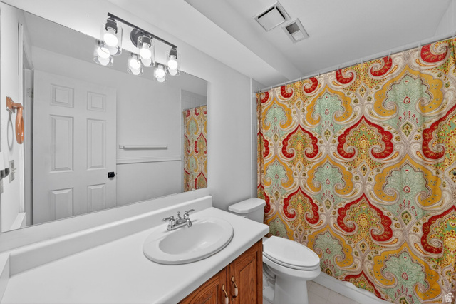 788 East Gables Street Midvale, UT 84047 - Photo 17 of 24 Bathroom featuring a vanity with a white countertop and integrated sink, a chrome two-handle faucet, and a wood-finish cabinet