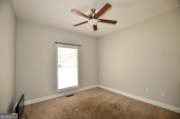 an empty room with a window and a ceiling fan
