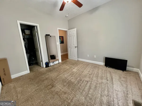 a view of an empty room with chandelier fan