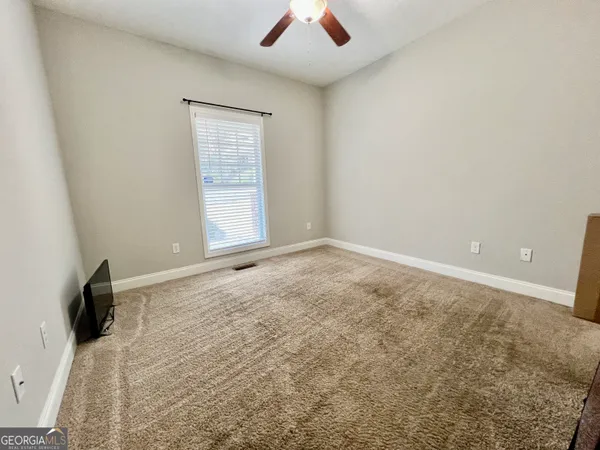 an empty room with ceiling fan and window