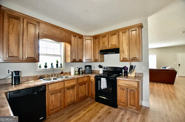 a kitchen with stainless steel appliances granite countertop a sink a stove top oven a refrigerator with wooden floors and cabinets