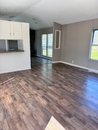 a view of an empty room with a window and wooden floor