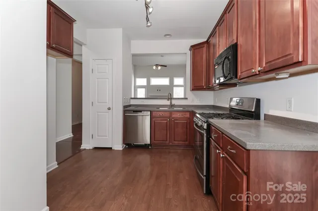 a kitchen with stainless steel appliances granite countertop a stove a sink dishwasher and a refrigerator with wooden floor