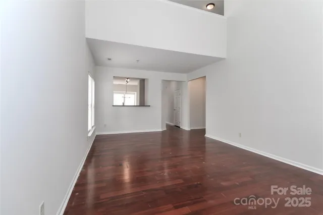 a view of an empty room with window and wooden floor