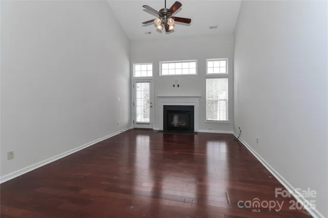 an empty room with wooden floor a fireplace and windows