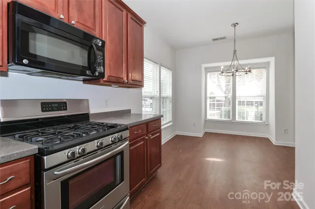 a kitchen with stainless steel appliances a stove a microwave and wooden floor