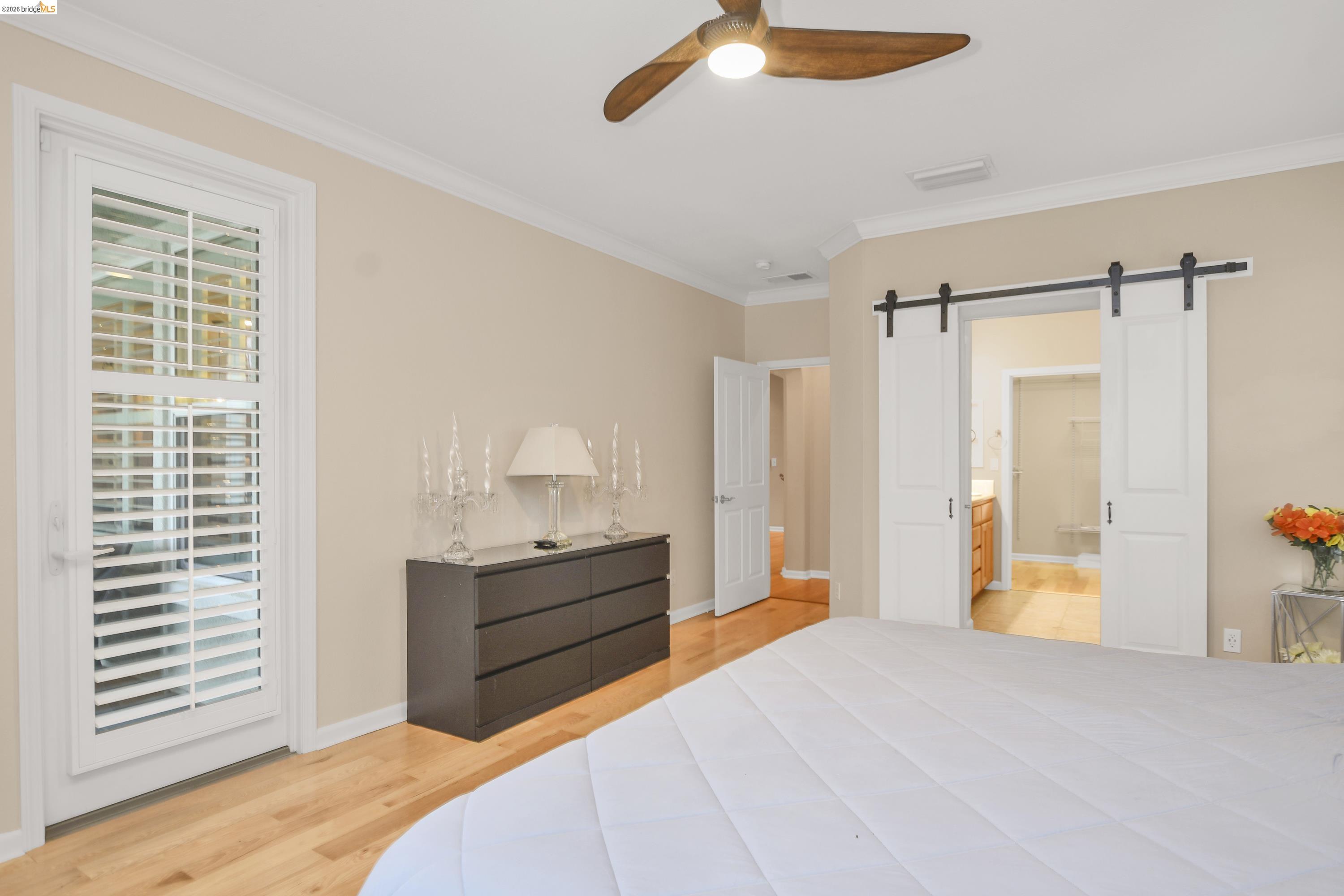 342 Desert Forest Court Rio Vista, CA 94571 - Photo 31 of 40 Bedroom featuring a barn door, light wood-style floors, crown molding, access to exterior, and ceiling fan