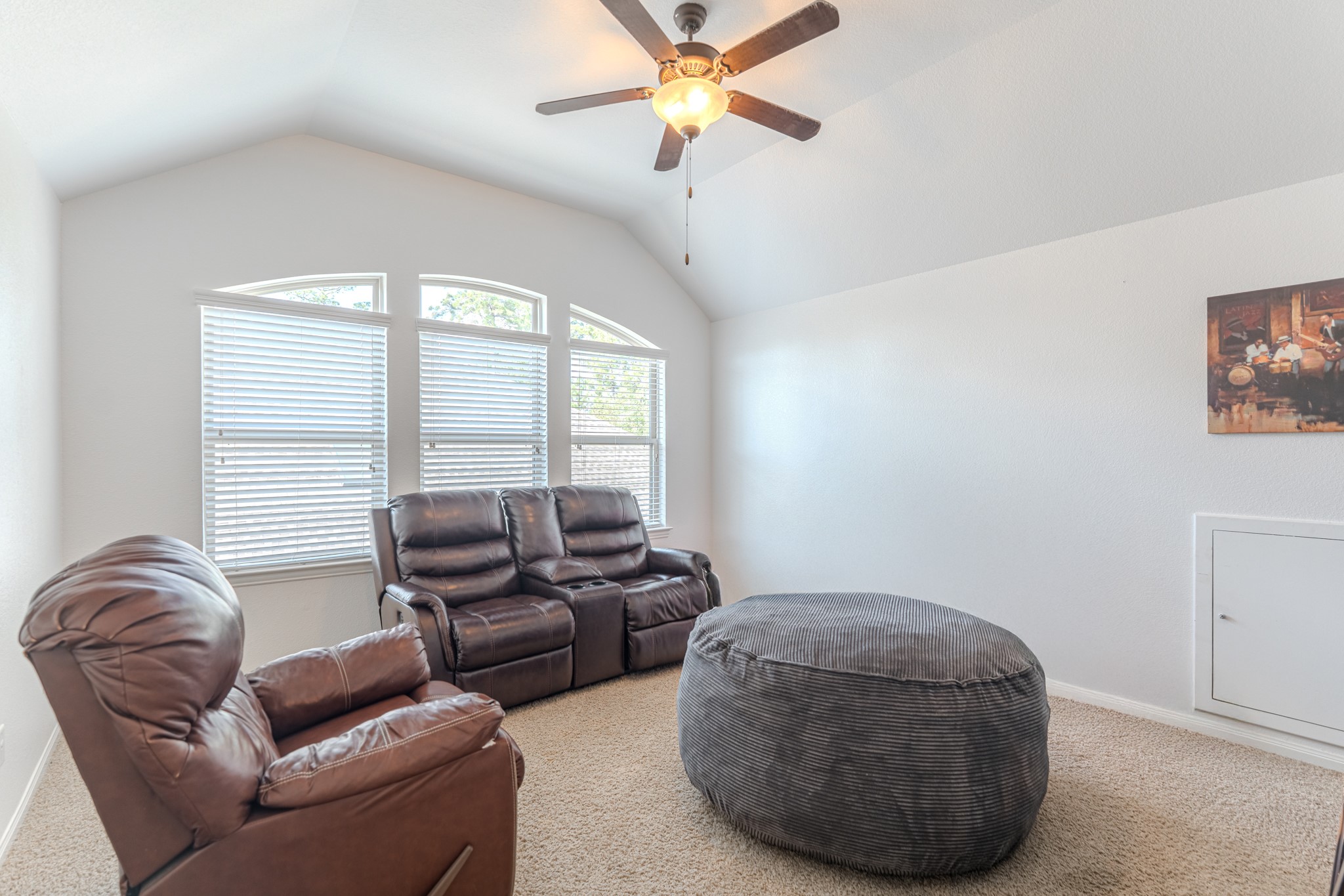 30 Fury Ranch Place The Woodlands, TX 77375 - Photo 32 of 47 This photo showcases a spacious open-concept living area with high ceilings and abundant natural light. The view from above highlights a cozy seating area near a fireplace, a stylish kitchen island with bar seating, and elegant wood flooring. Large windows enhance the airy atmosphere, perfect for modern living.