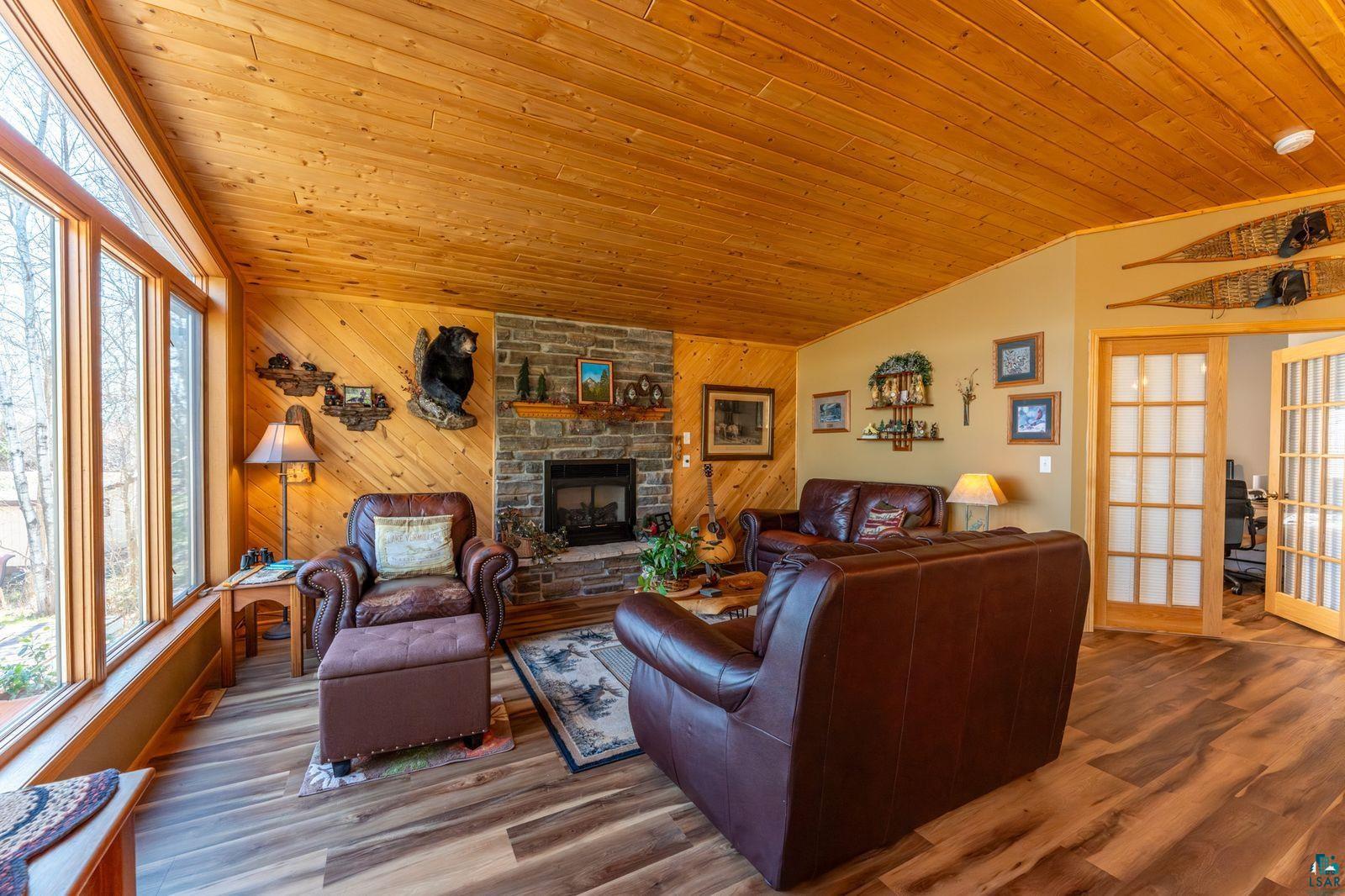 4452 Moccasin Point Road Tower, MN 55790 - Photo 8 of 44 Living area featuring wood-finish flooring, a stone-clad fireplace, and extensive wood paneling on walls and ceiling