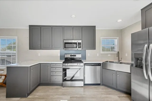 a kitchen with stainless steel appliances granite countertop a stove a sink dishwasher a refrigerator and a microwave oven with wooden cabinets