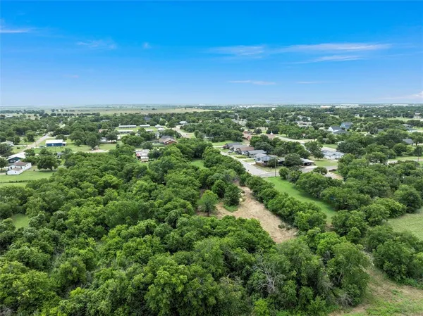 an aerial view of residential houses with outdoor space and trees