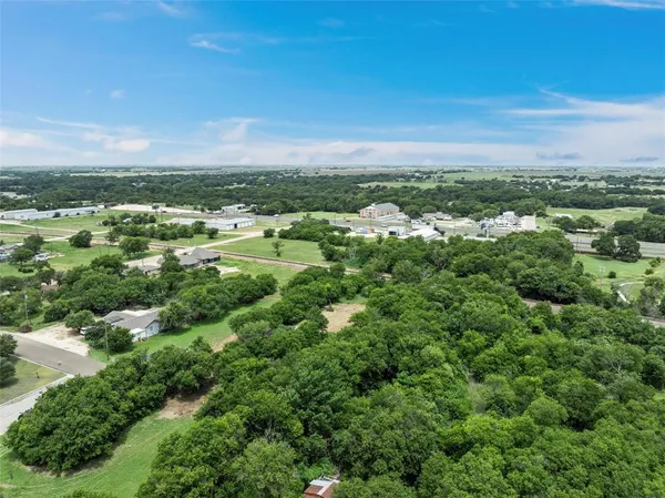 an aerial view of residential houses with outdoor space and trees