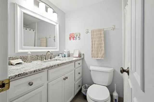 a bathroom with a granite countertop toilet sink and mirror