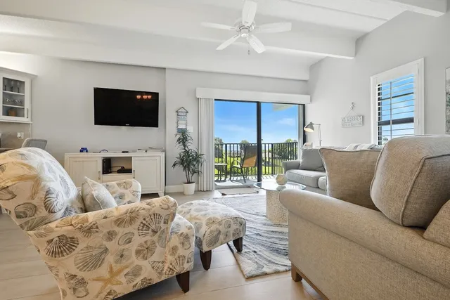 a living room with furniture a flat screen tv and a large window