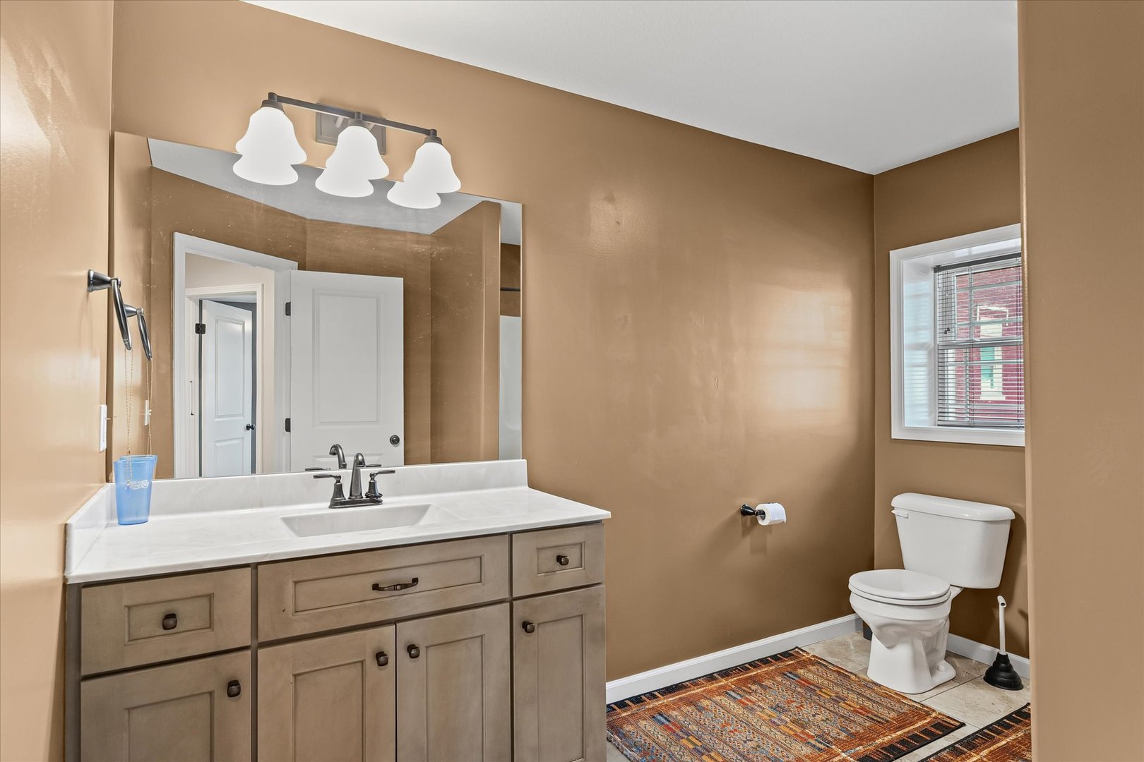 103 1st Street Strawn, IL 61775 - Photo 32 of 50 a bathroom with a sink a toilet a mirror and a window