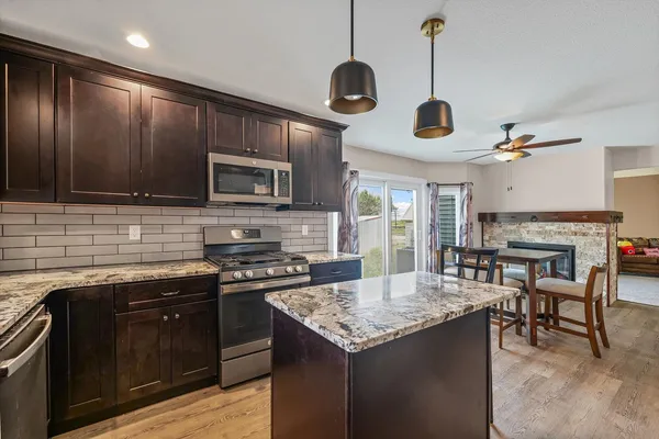 a kitchen with granite countertop stainless steel appliances cabinets a sink and a wooden floor