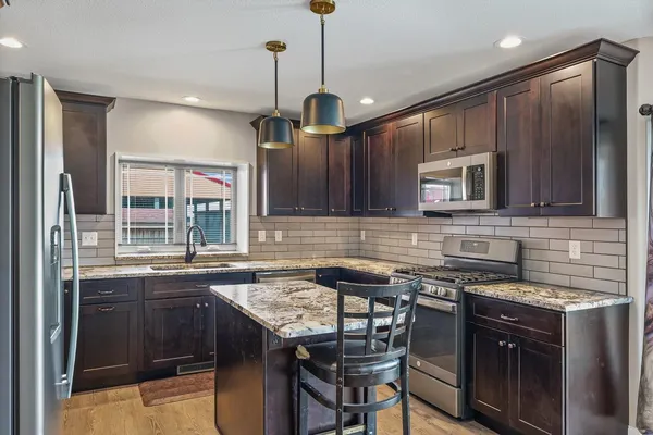 a kitchen with stainless steel appliances granite countertop wooden cabinets a stove a sink and a microwave