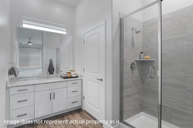a bathroom with a granite countertop sink two mirror and shower