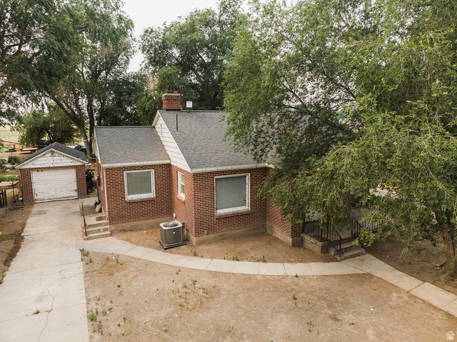 3885 West 4500 S Road Delta, UT 84624 - Photo 6 of 24 Brick exterior residence featuring a detached garage, a concrete driveway, and a walkway leading to the front entry