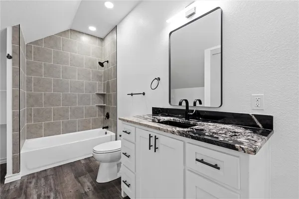 a bathroom with a granite countertop sink a toilet and a bathtub