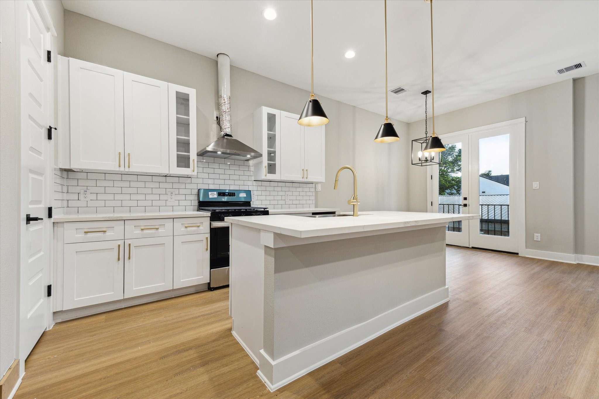 812 Thornton Road, Unit B Houston, TX 77018 - Photo 21 of 39 a kitchen with stainless steel appliances kitchen island granite countertop a stove a sink and white cabinets with wooden floor