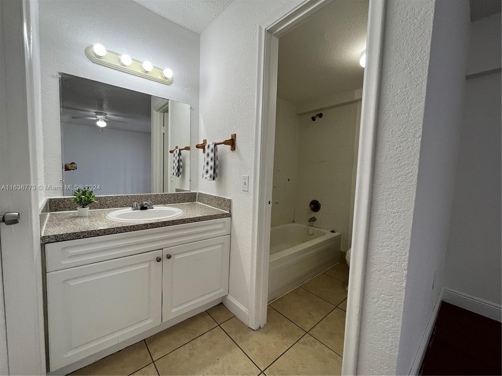 Hialeah Hialeah, FL 33012 - Photo 16 of 21 a bathroom with a granite countertop sink two mirror and a bathtub