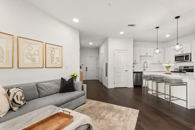 a living room with stainless steel appliances kitchen island granite countertop furniture wooden floor and a view of kitchen